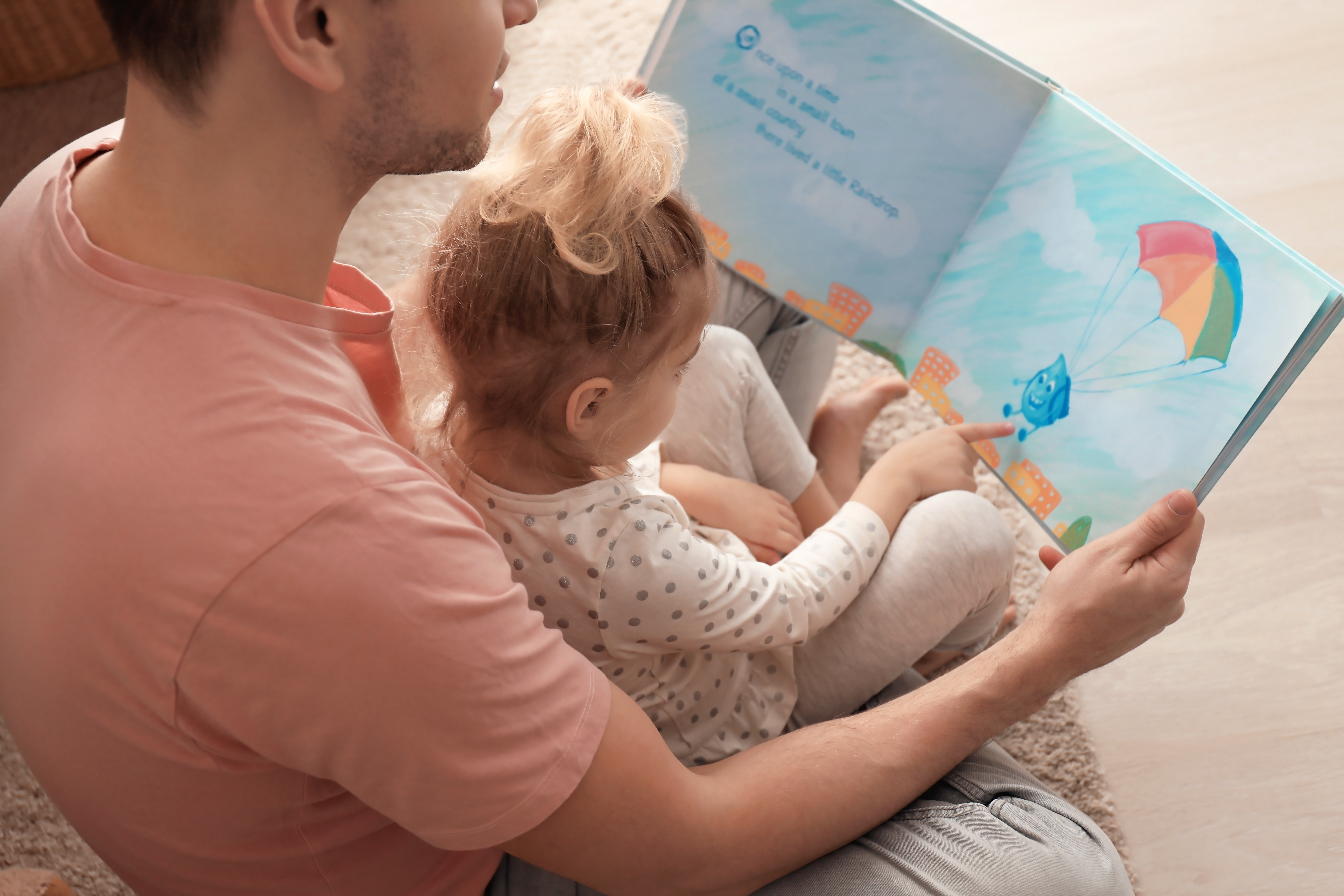 A child reading a picture book with an adult